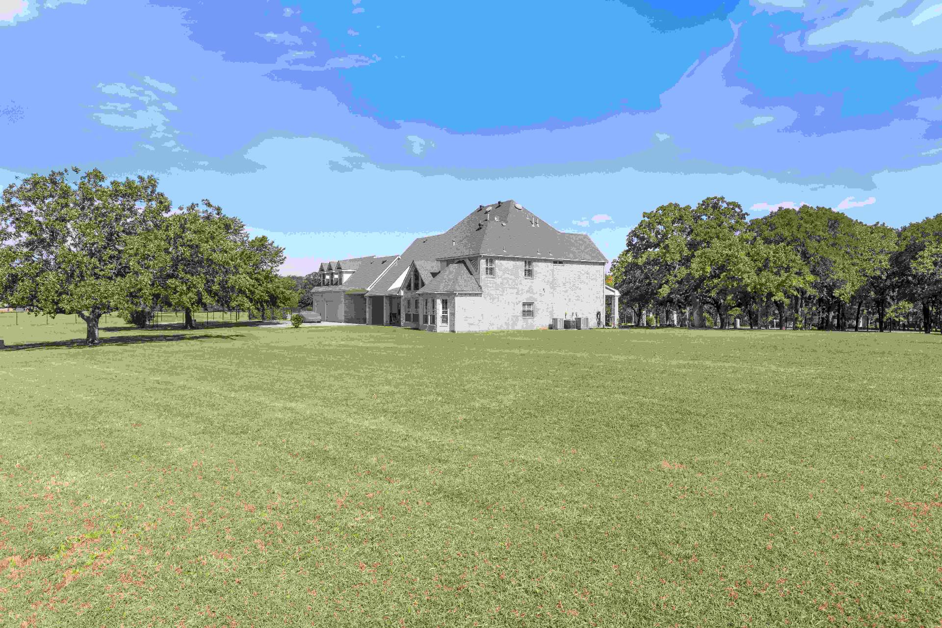 Rear elevation of the home framed by mature oaks