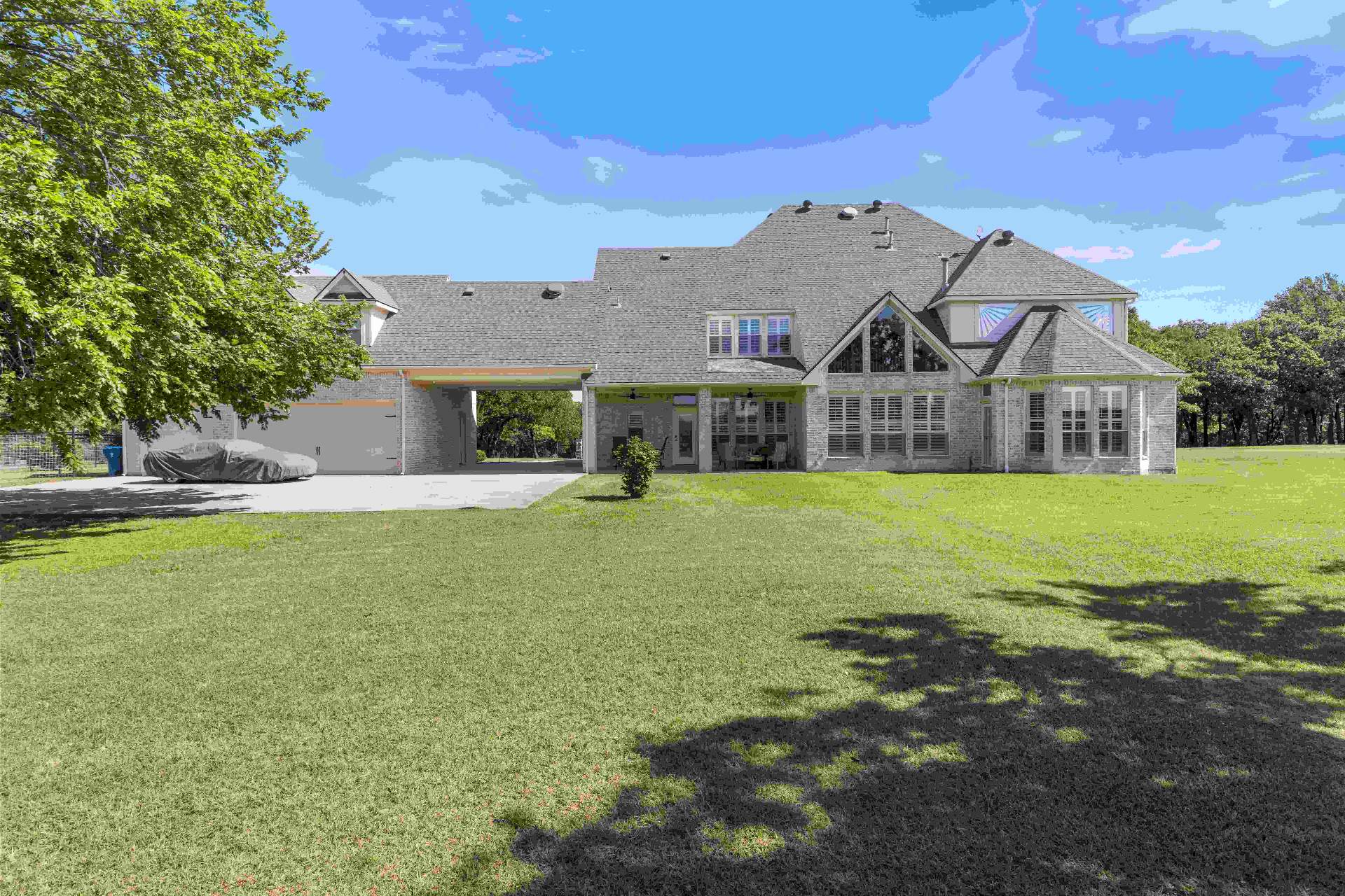 Wide rear elevation with covered patio, porte-cochere, and open lawn