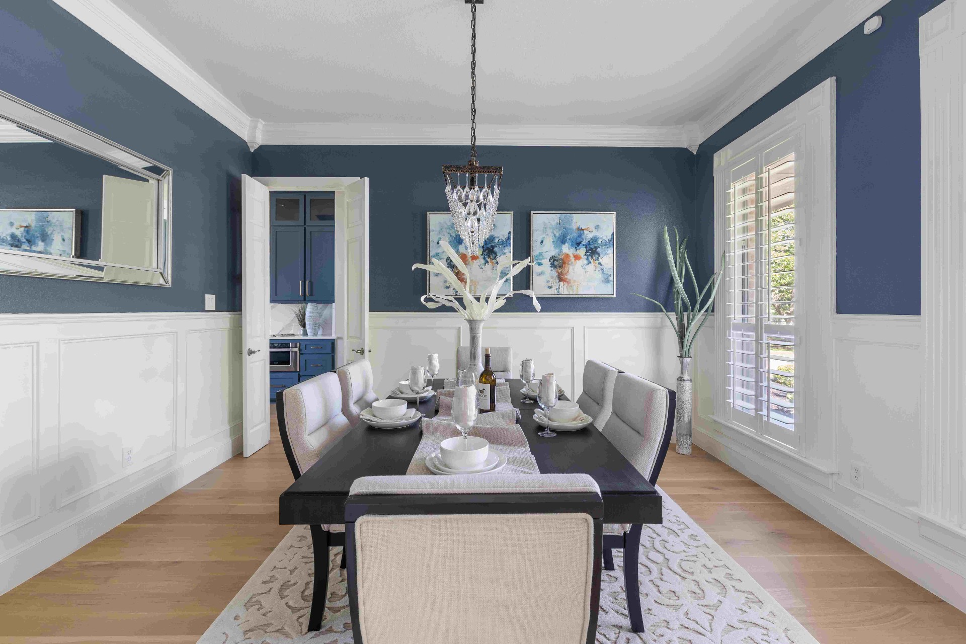 Formal dining room with navy walls, wainscoting, and crystal chandelier