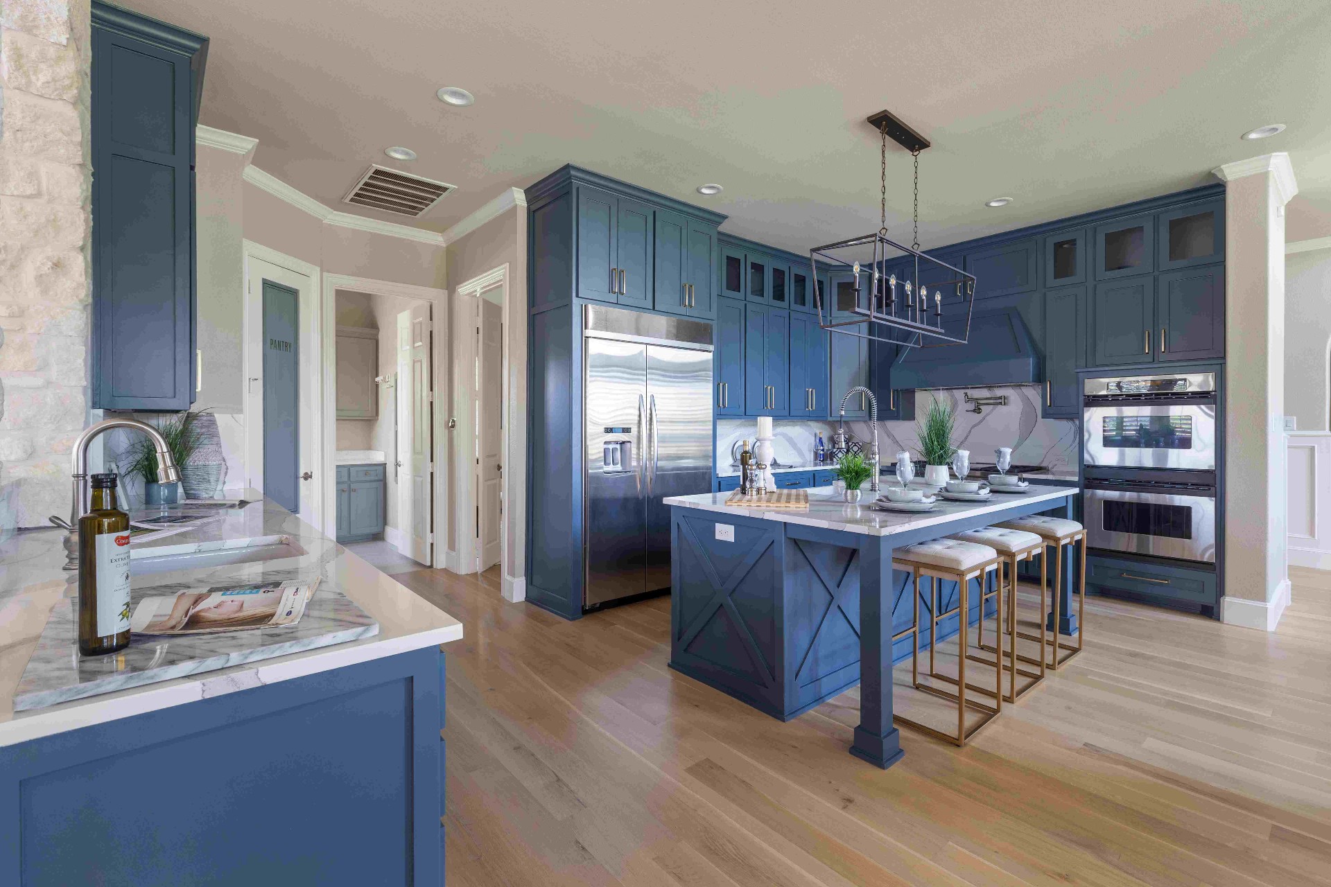 Chef kitchen with navy cabinetry, marble island, double oven and built-in fridge