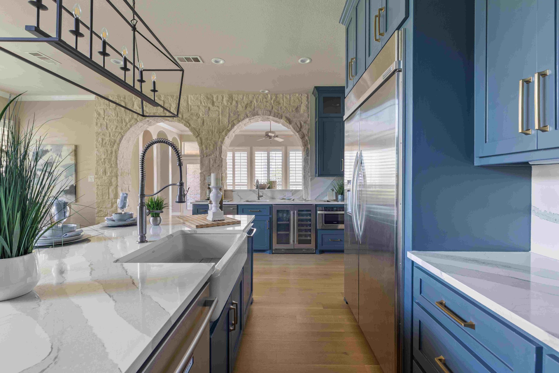 Galley kitchen view with built-in fridge, marble island, and stone archways