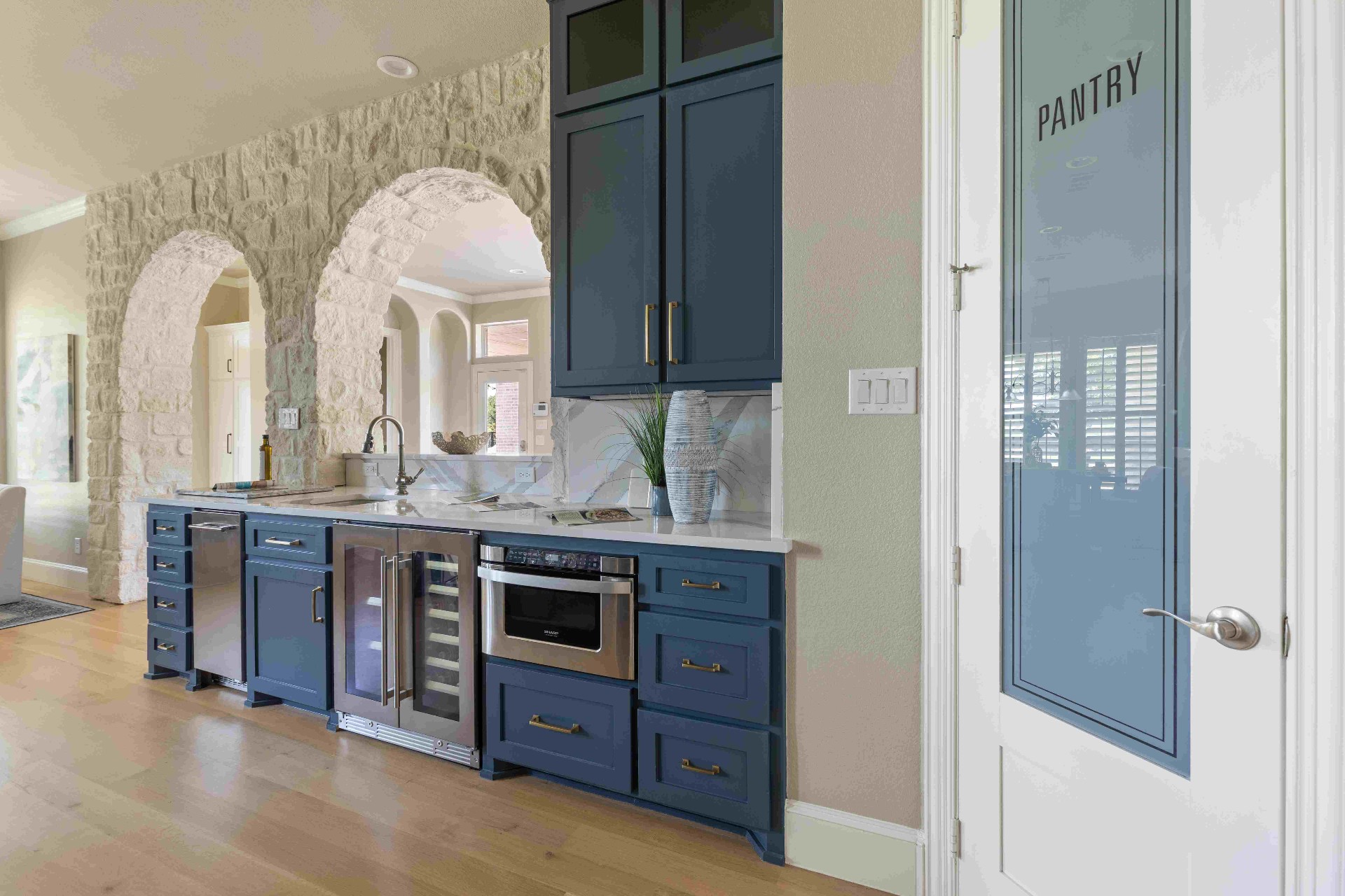 Butler's pantry with wine fridge, microwave drawer, and stone archways