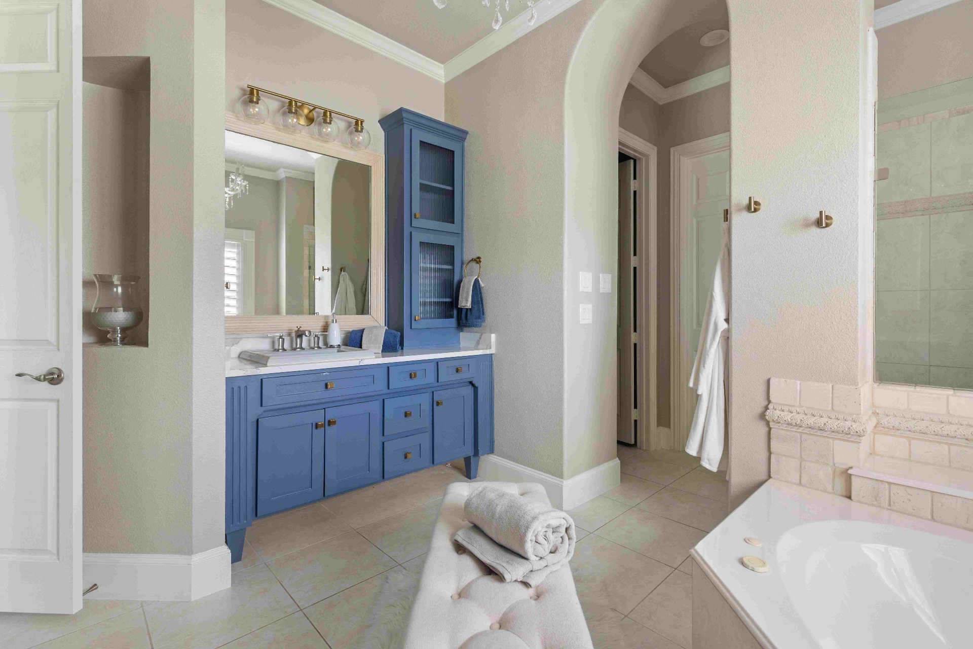 Primary bath vanity with arched doorway and chandelier