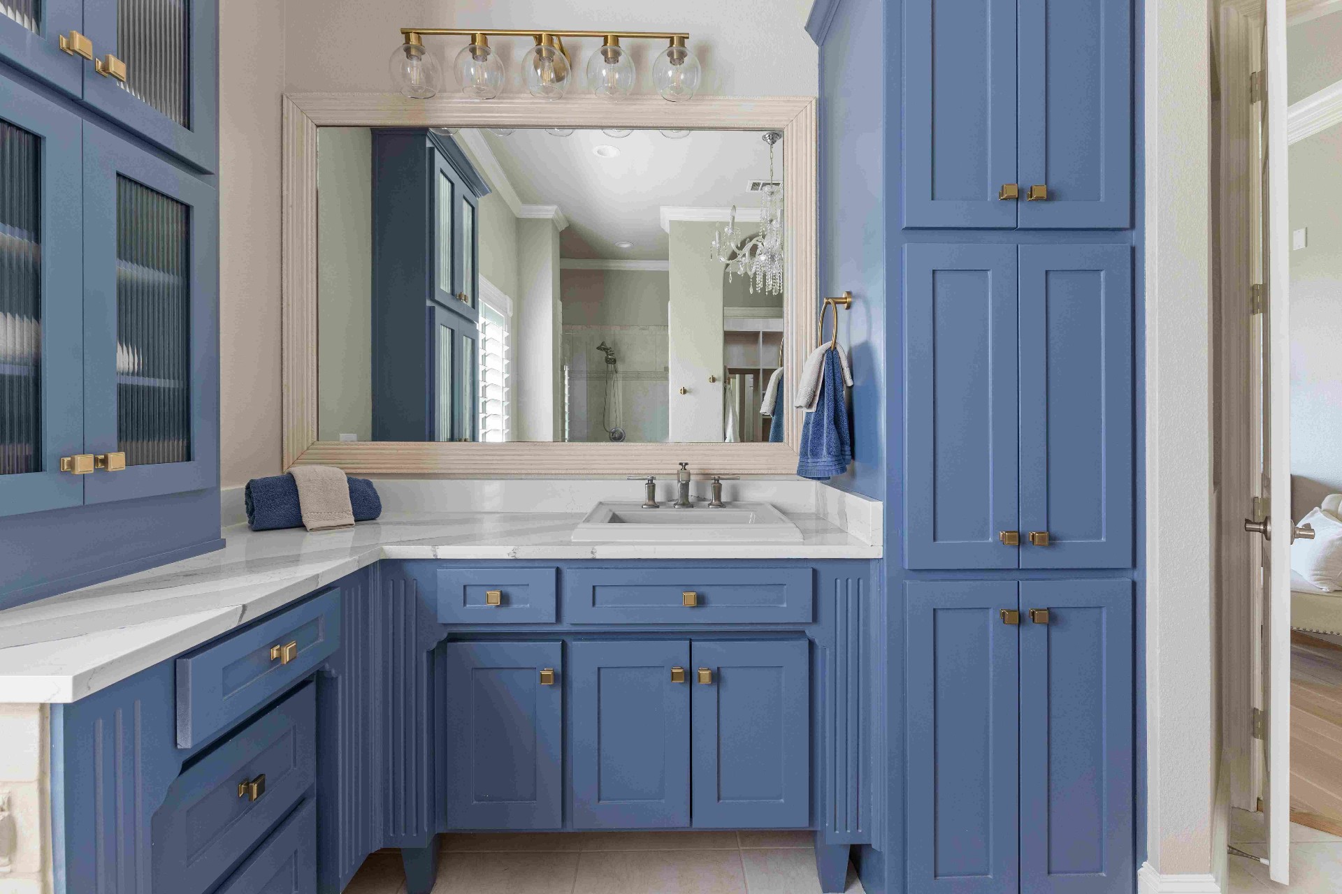 Primary bath with navy blue cabinetry, brass hardware, and marble counters