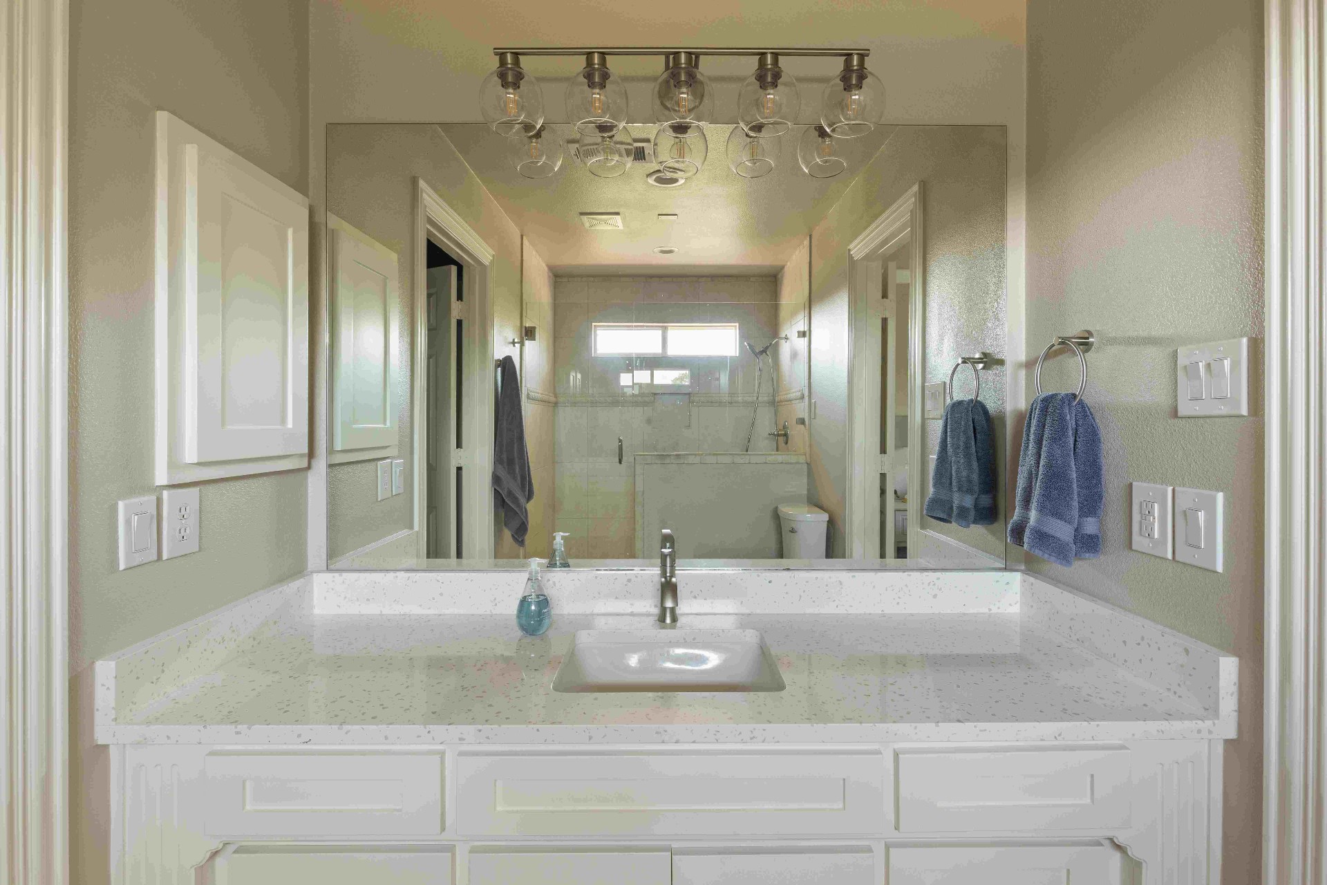 Secondary bath with quartz vanity, glass globe lighting, and walk-in shower