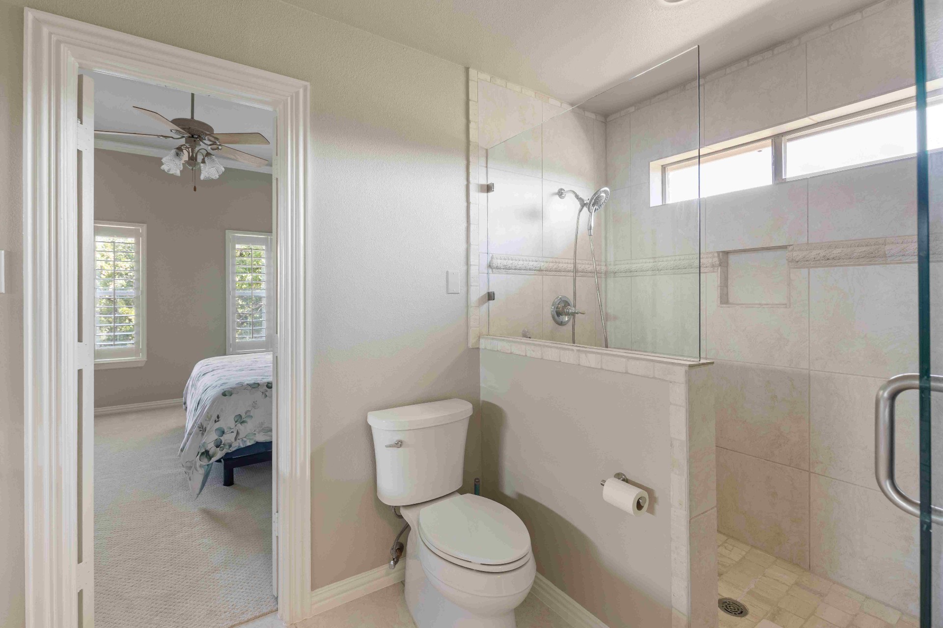 Secondary bath with walk-in tile shower, glass partition, and adjoining bedroom view
