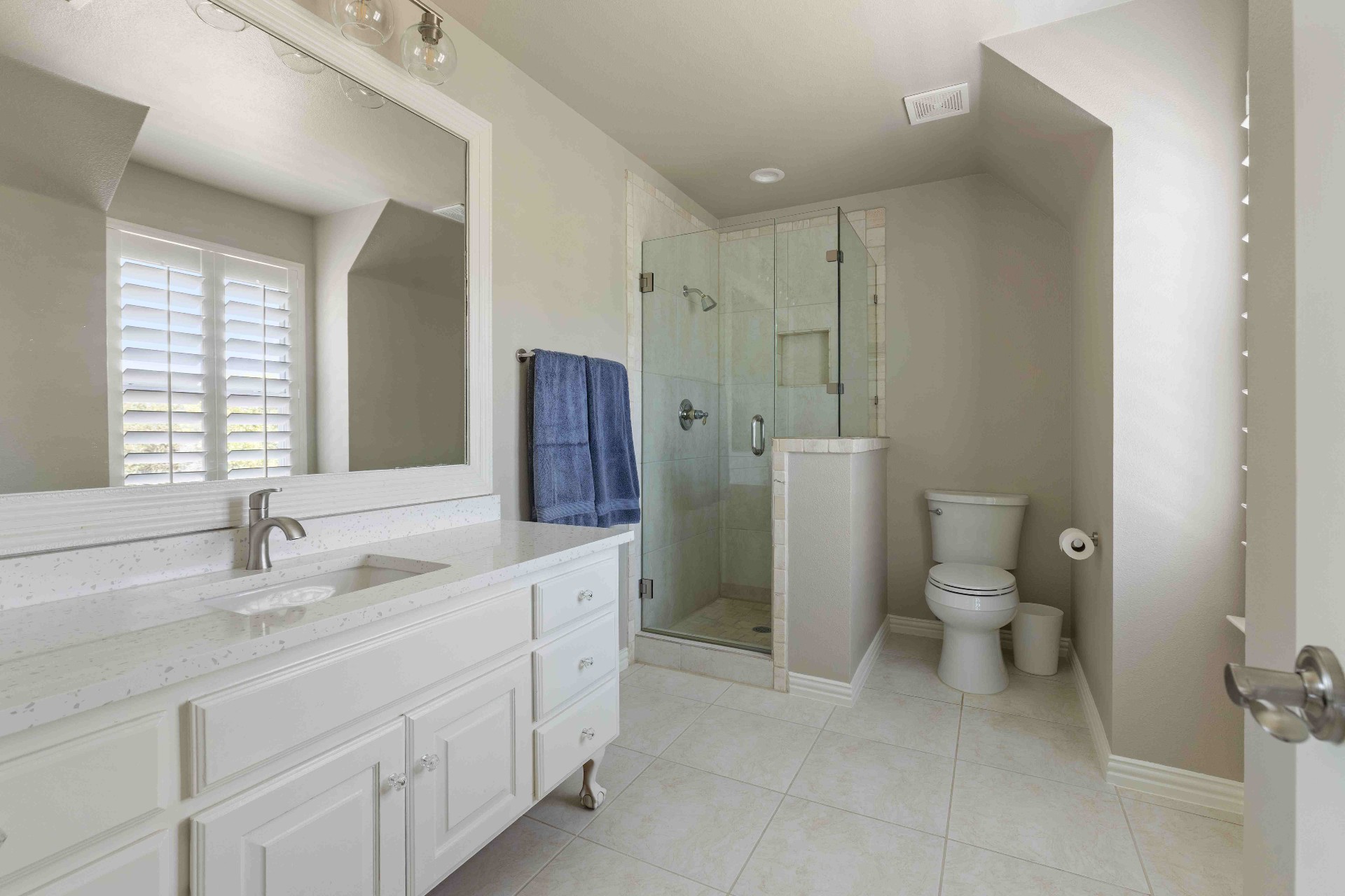 Secondary bathroom with quartz vanity and frameless glass shower