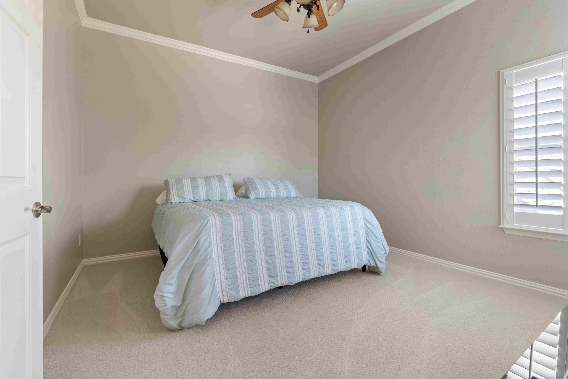 Guest bedroom with plantation shutters and crown molding